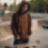 A skateboarder wearing a dark brown hoodie in an urban skate park.